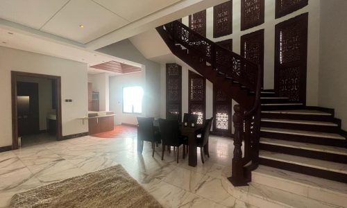 For rent, a luxurious villa in Juffair boasting a spacious living room with an elegant staircase connecting to a captivating dining area.