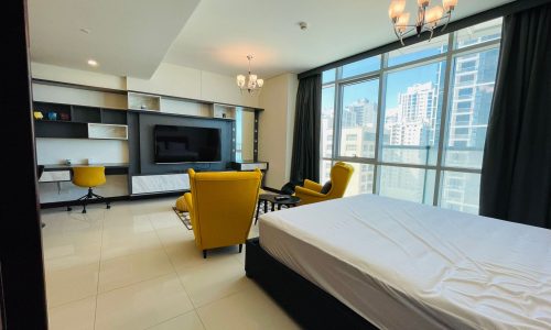 A luxury studio bedroom with a bed, tv, and a stunning view of Juffair city.