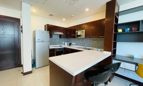 A small, modern living kitchen in Juffair with a refrigerator and microwave.