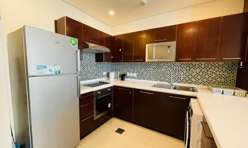 A modern living kitchen with stainless steel appliances and wooden cabinets.