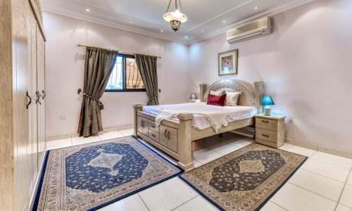 A villa bedroom with a bed and rugs in the Al-Hajiyat area.