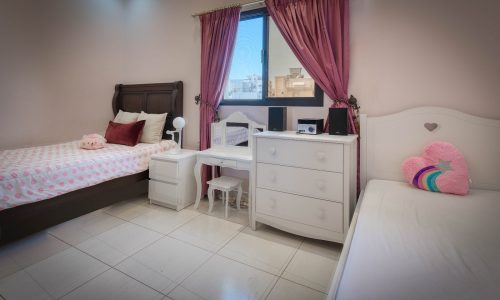 Al-Hajiyat villa for sale, featuring a bedroom with pink curtains and a window.