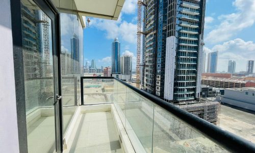 A luxury 1BR apartment with a balcony overlooking the cityscape of tall buildings in Seef.