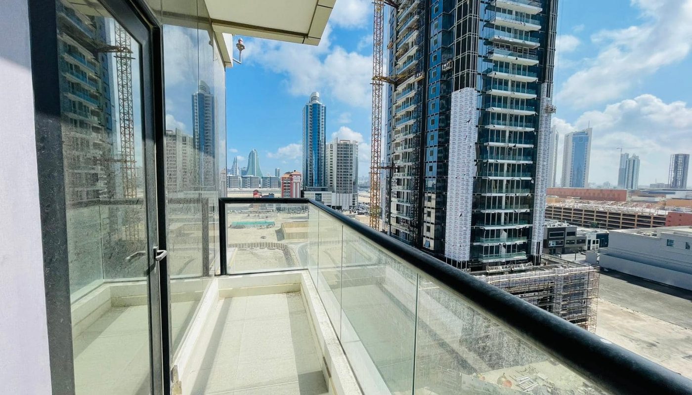 A luxury 1BR apartment with a balcony overlooking the cityscape of tall buildings in Seef.