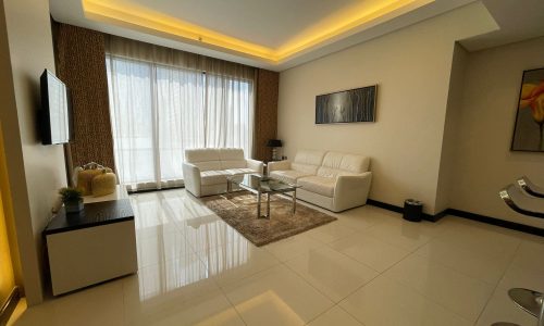 A living room with white furniture and a flat screen tv.