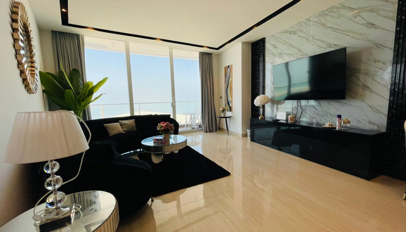 A living room with a flat screen tv and a view of the ocean.