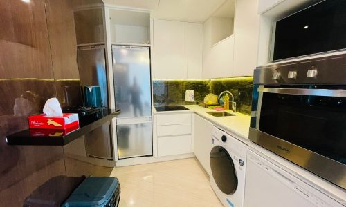 A kitchen with a washing machine and refrigerator.