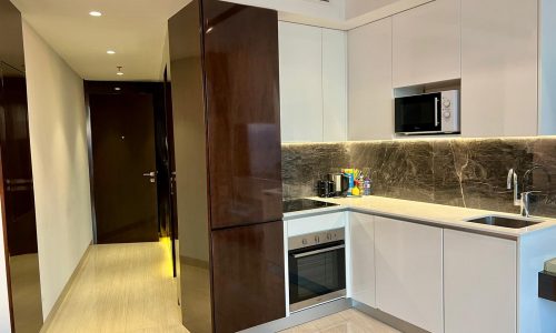 Studio kitchen interior in a prestigious building with built-in appliances and white cabinetry at Bahrain Water Bay.