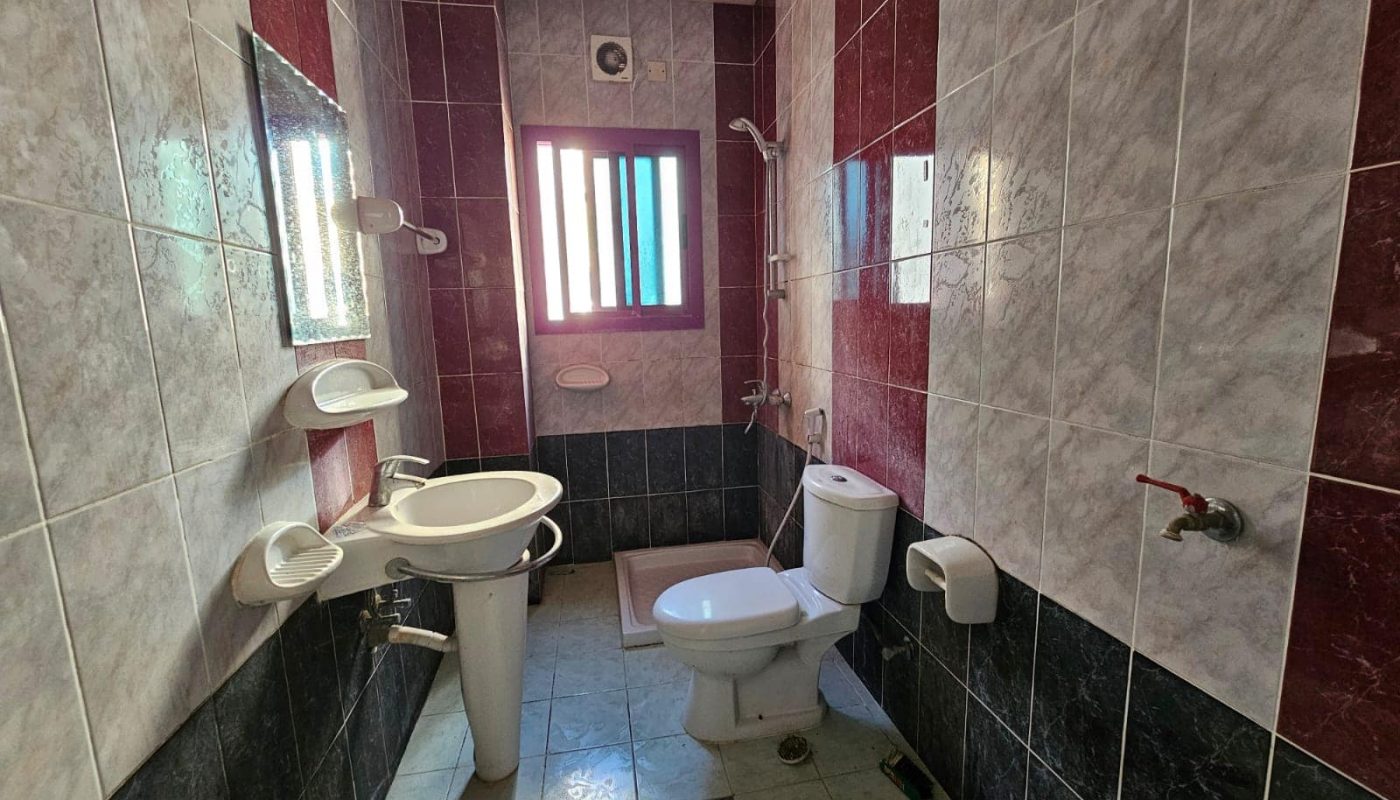 A flat with red and white tiles and a toilet.