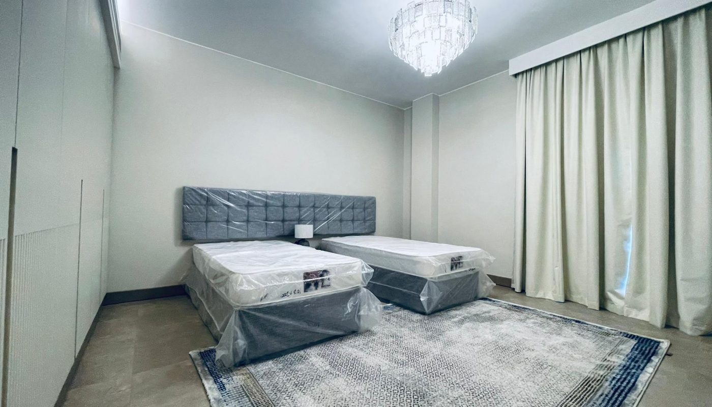 A bedroom with two beds and a chandelier.