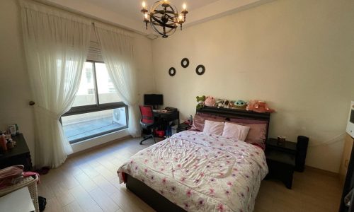 A furnished bedroom with a bed, dresser, and TV.