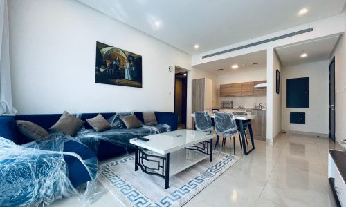 An amazing apartment for rent with a living room featuring a blue couch and a dining table in Juffair.