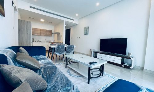 A living room in an apartment for rent, with a blue couch and TV.