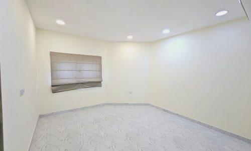 Brightly lit empty apartment for rent in Saar with tiled floor and a single window with blinds.