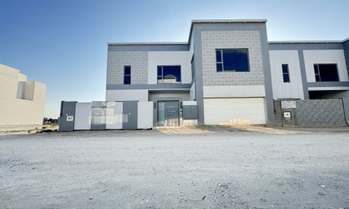 Newly constructed modern villa in Saraya 2 with large front gate and clear blue sky.