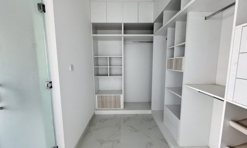 Modern villa for sale: Empty walk-in closet with white built-in shelves and drawers.