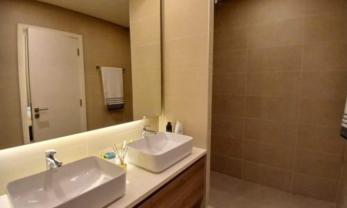 Modern bathroom interior with double sinks and beige tiles in a luxury apartment.