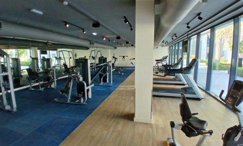 Modern gym interior with various exercise equipment and wooden flooring, located in the luxury apartment at MG Mall.