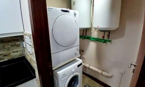 A laundry room with a stacked washer and dryer, a water heater, and Auto Draft.