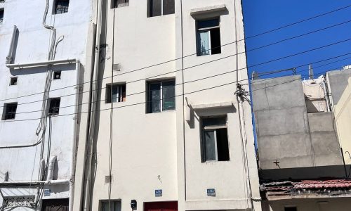 Salmaniya multi-story buildings with red doors under a clear blue sky, building for sale.