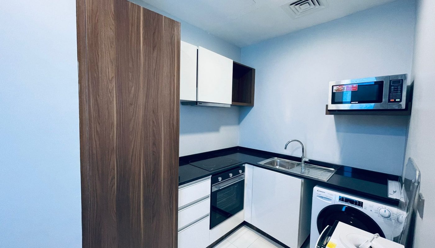 Eye-catching, modern compact kitchen with wood-finish cabinets, stainless steel appliances, and white goods.