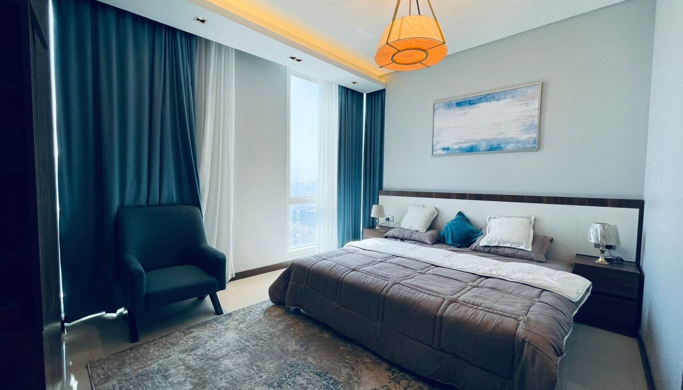Modern bedroom in an amazing apartment with a large bed, elegant lighting fixture, and a scenic window view.