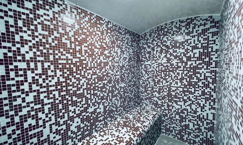 A tiled room in an amazing apartment with a mosaic pattern in various shades.