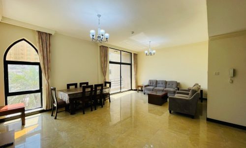 Spacious living room with dining area, large windows, and contemporary furniture in a Juffair apartment for rent.