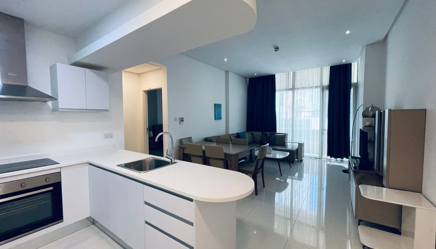 A modern kitchen with white cabinetry opens into a living area with contemporary Auto Draft furniture.
