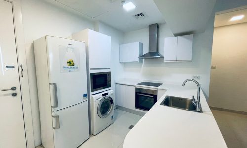 Modern kitchen interior with white appliances, including a refrigerator, oven, microwave, and washing machine, with an Auto Draft countertop.