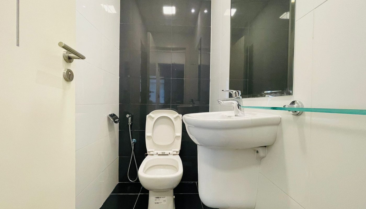 A clean and modern bathroom with a toilet and a sink, featuring dark floor tiles and white wall tiles, auto draft.