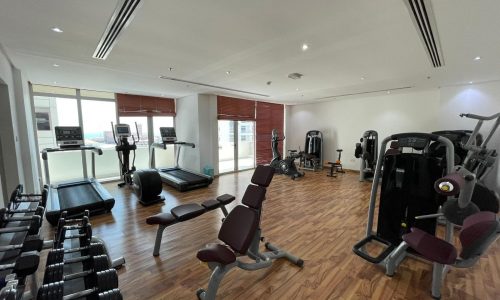 Modern gym with various exercise equipment, wooden flooring, and Auto Draft.