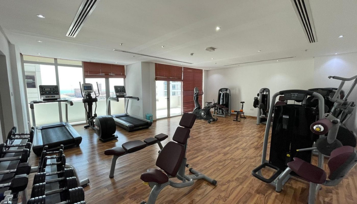 Modern gym with various exercise equipment, wooden flooring, and Auto Draft.