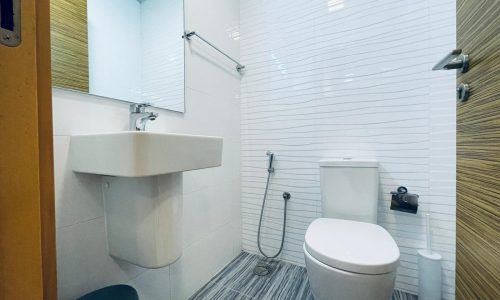 A modern bathroom interior with a wall-mounted sink, toilet, and accessible shower area.