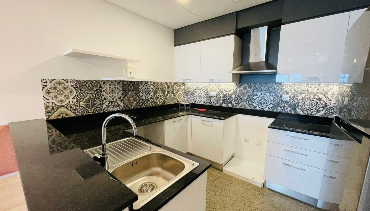 A luxury apartment with a modern kitchen featuring stainless steel sink, patterned backsplash, and white cabinets in Juffair.