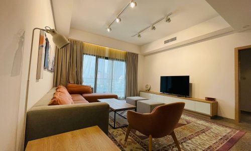 Modern living room in a luxury 1 BR apartment in Juffair with a comfortable seating area, television, and warm lighting.