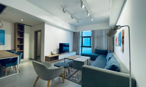 A modern living room with a gray sofa, track lighting, and contemporary auto-draft furnishings.