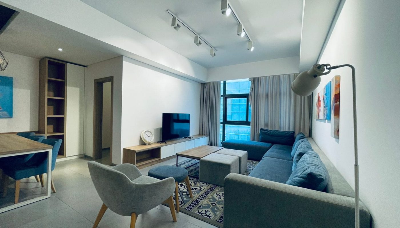 A modern living room with a gray sofa, track lighting, and contemporary auto-draft furnishings.