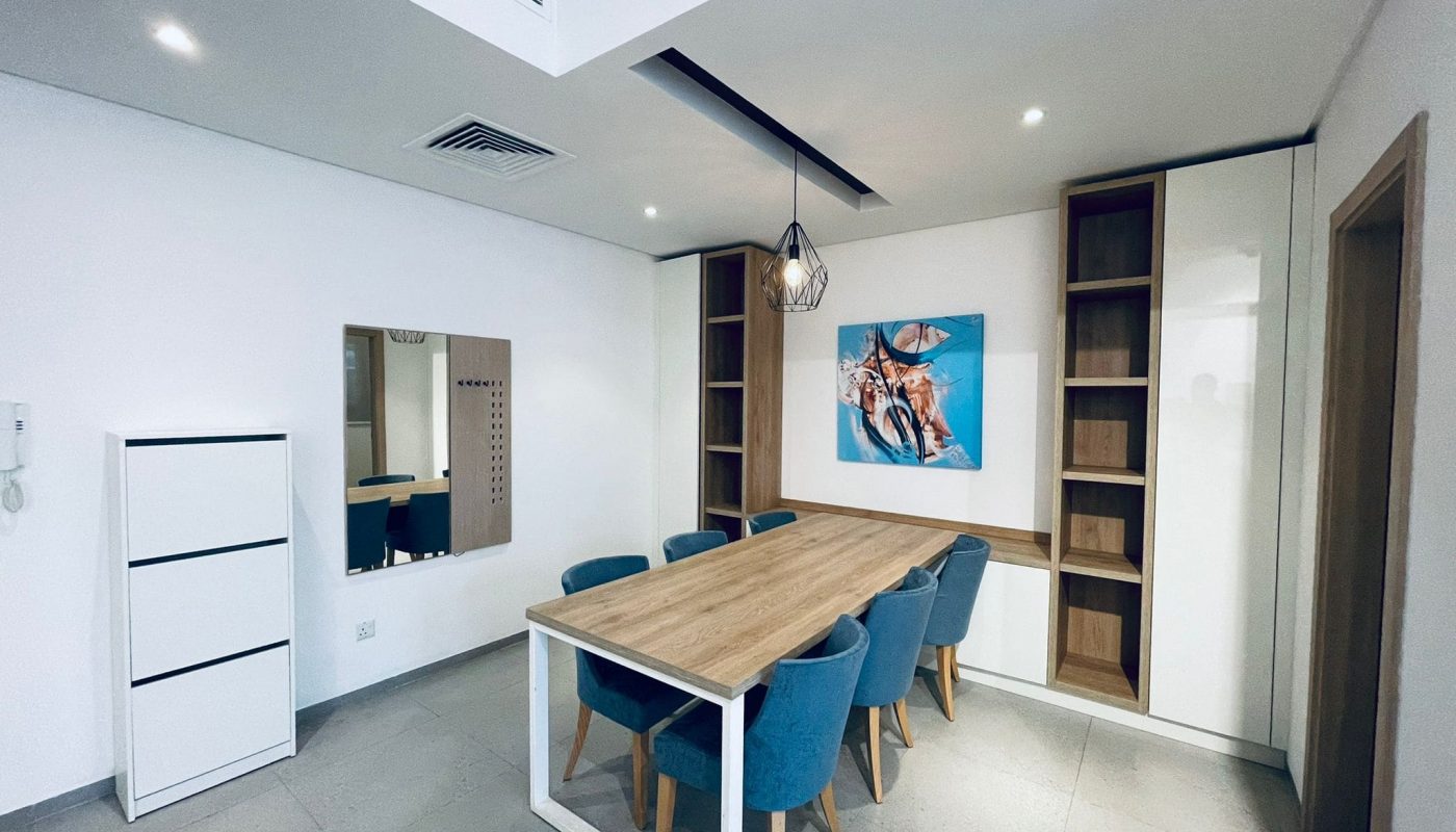 Modern dining room with a wooden table, blue chairs, and Auto Draft abstract art on the wall.