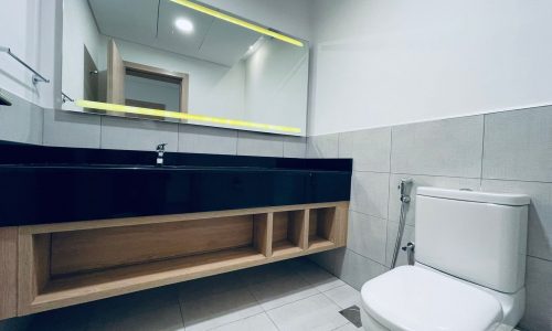 Modern bathroom interior with auto draft led mirror lighting, a wall-mounted vanity, and a toilet.