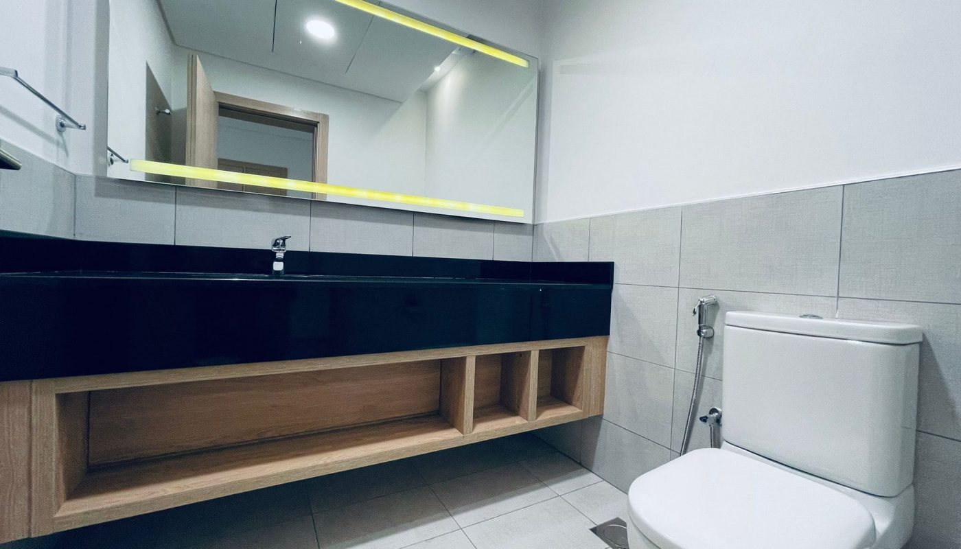 Modern bathroom interior with auto draft led mirror lighting, a wall-mounted vanity, and a toilet.