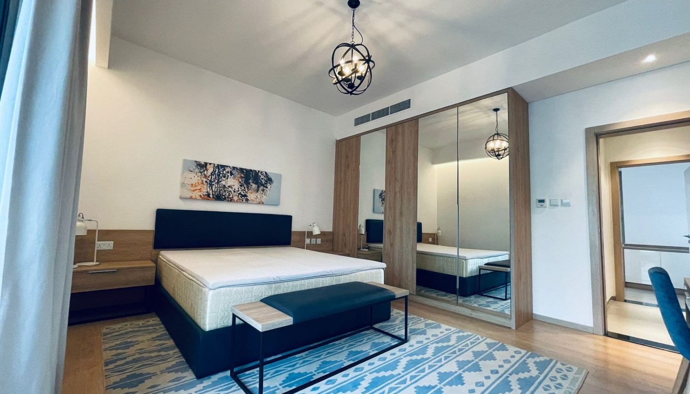 Modern bedroom with a patterned blue rug, wooden furniture, auto draft, and abstract wall art.