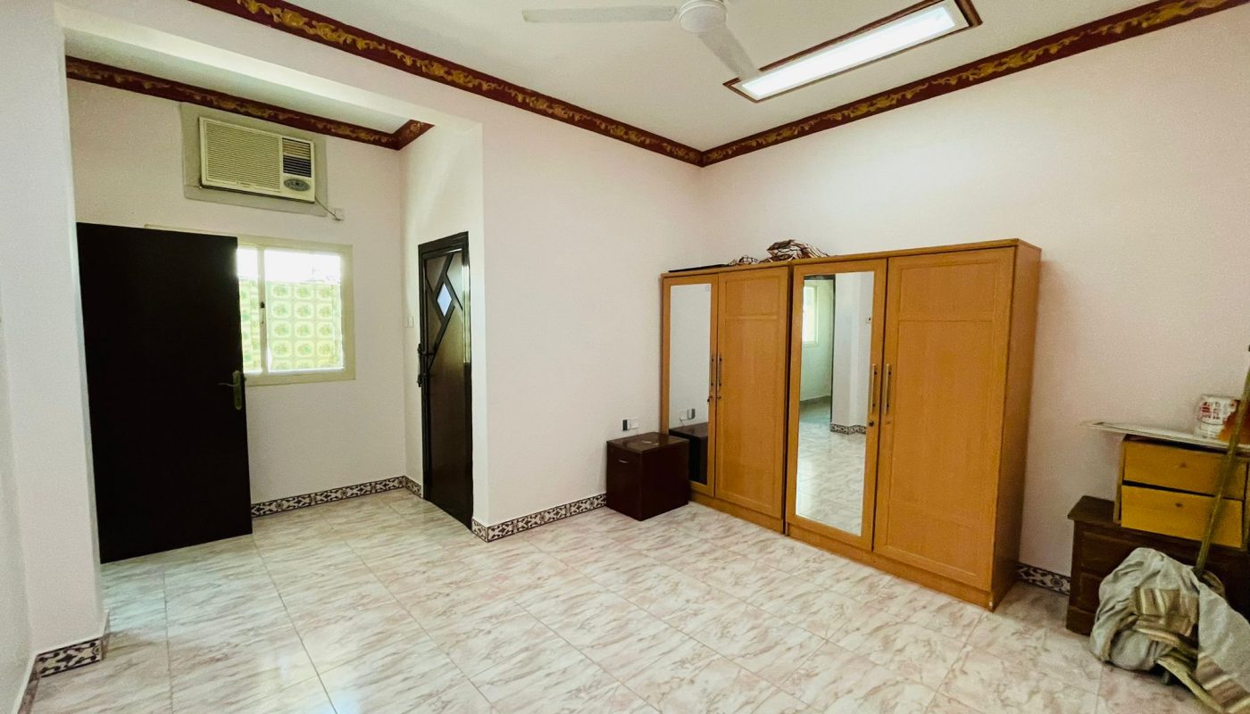 A spacious 2BR Villa in Ras Rumman with a large wardrobe, an air conditioner, a ceiling fan, and tiled flooring.