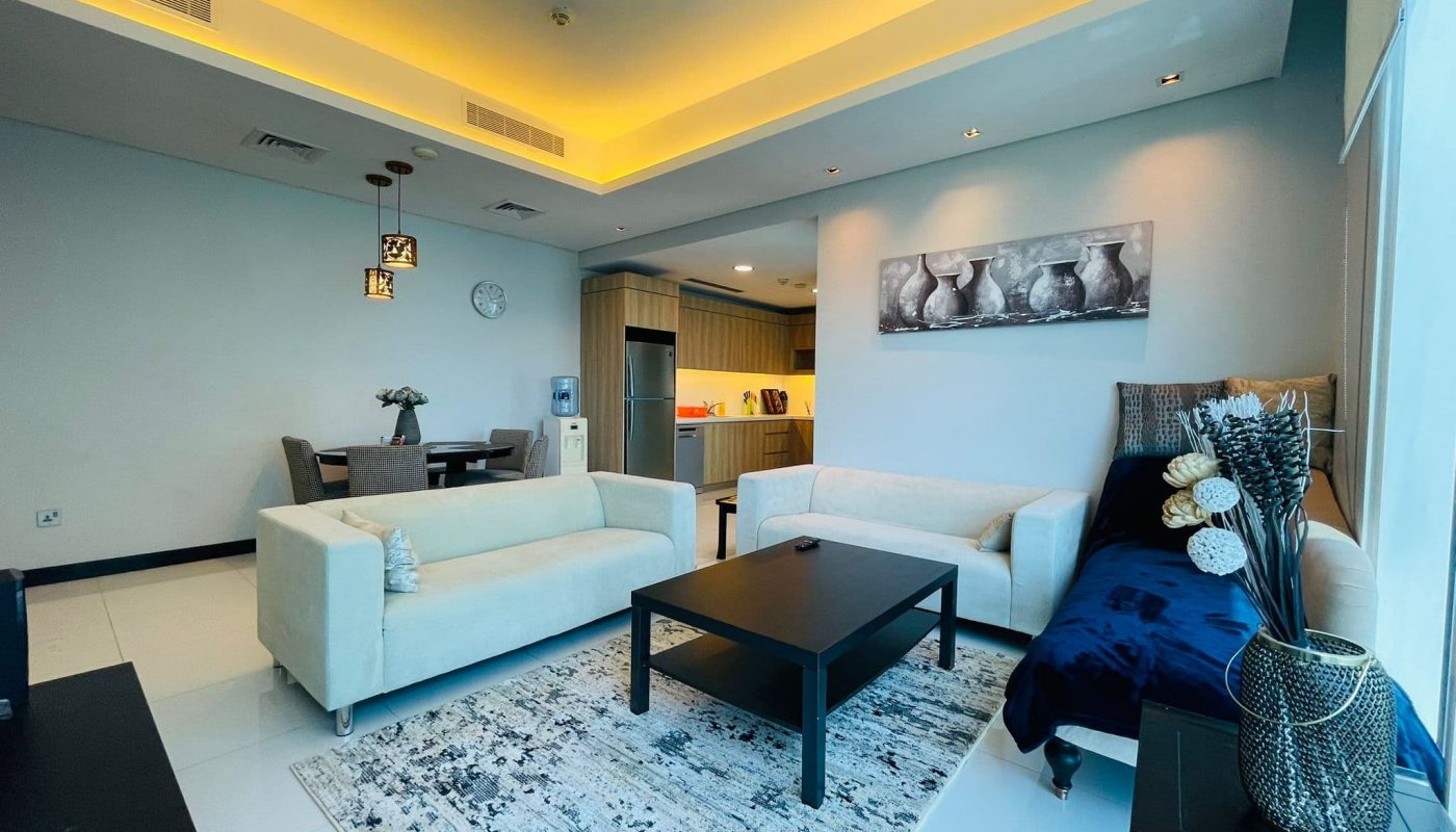 Luxury 2BR apartment for rent featuring a modern living room interior with comfortable seating, a coffee table, decorative lighting, and an adjoining kitchen area.