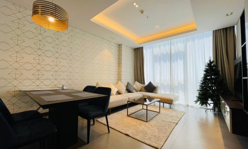 Contemporary living room with geometric wallpaper, a sectional sofa, and an elegant lighting fixture.