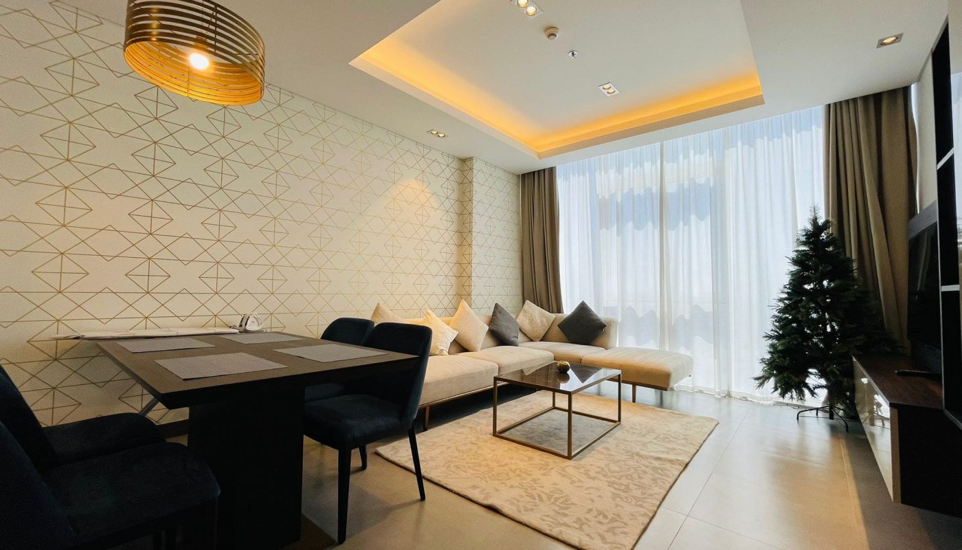 Contemporary living room with geometric wallpaper, a sectional sofa, and an elegant lighting fixture.