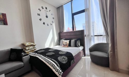 Modern flat for sale in Juffair with a large window, a wall clock design, and contemporary furnishings.