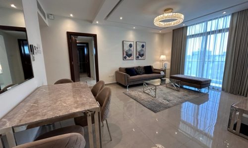 A modern living room with a dining area in luxury apartments, featuring marble floors, contemporary furniture, and large windows with curtains.