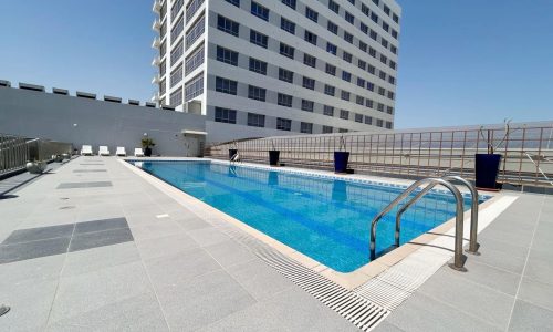 Rooftop swimming pool with clear blue water next to a modern high-rise building under a bright blue sky, marked as Auto Draft.