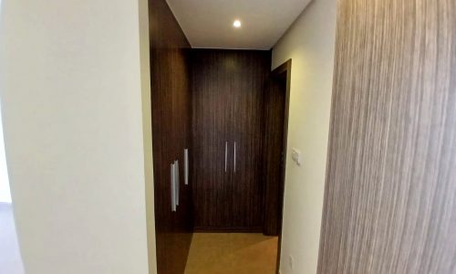 A modern hallway with beige walls, a dark wooden door, and simple auto-draft lighting.